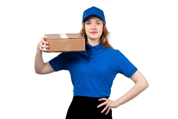 A front view young female courier in uniform holding delivery package smiling