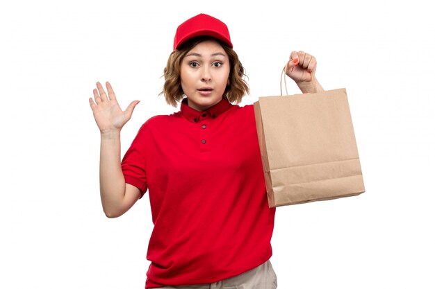 A front view young female courier in uniform holding delivery package