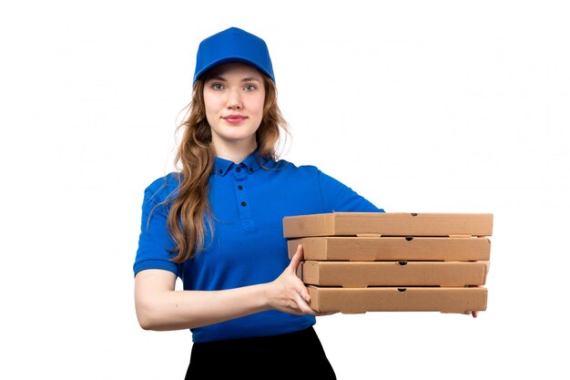 A front view young female courier in uniform holding delivery pizza boxes smiling