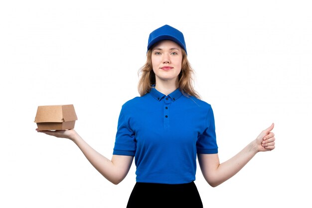 A front view young female courier in uniform holding food delivery package smiling