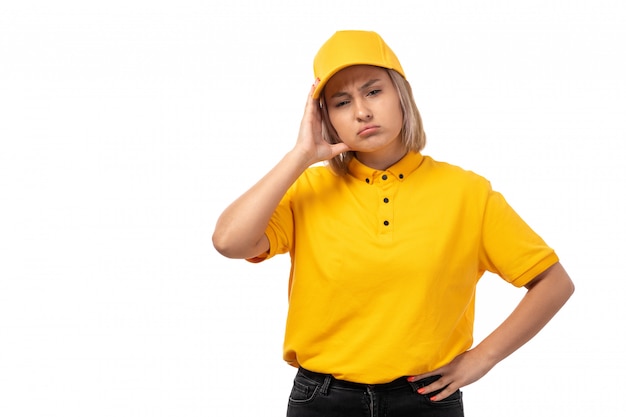 A front view young female courier in yellow shirt yellow cap and black jeans posing