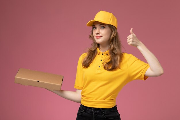 진한 분홍색 배경 유니폼 배달 서비스 색상에 음식 배달 상자를 들고 노란색 유니폼 노란색 케이프 전면보기 젊은 여성 택배