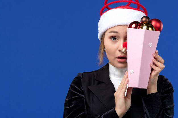 Free photo front view young female covering her face with toys on a blue wall emotion new year holiday