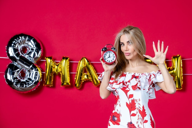 Front view young female in cute dress holding clock on red color