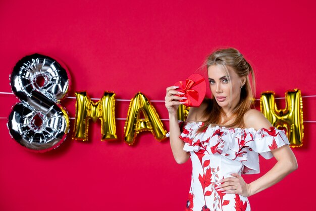 Front view young female in cute dress holding present on decorated red