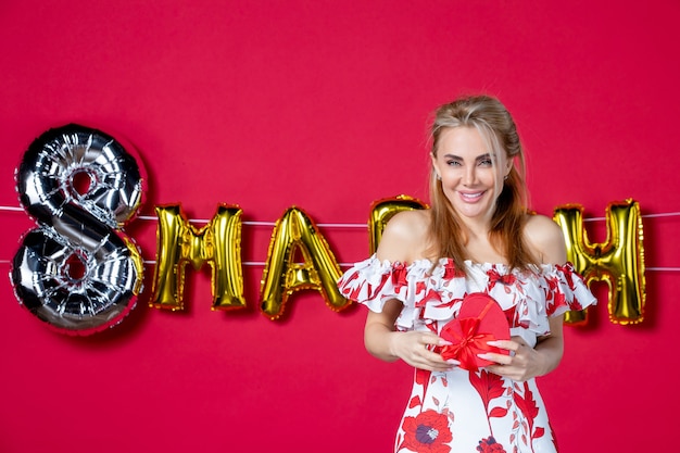 Front view young female in cute dress holding present on decorated red