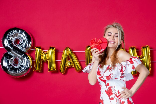 Front view young female in cute dress holding present on decorated red