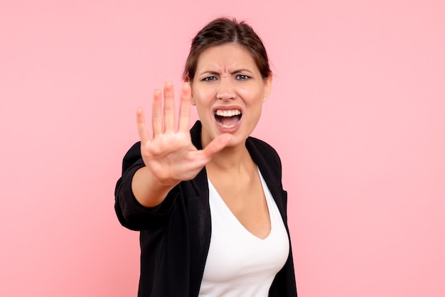 Front view young female in dark jacket angrily asking to stop on a pink background