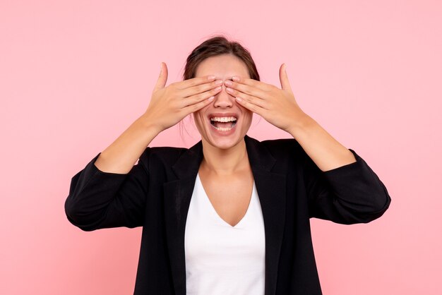 Front view young female in dark jacket covering her eyes on pink background