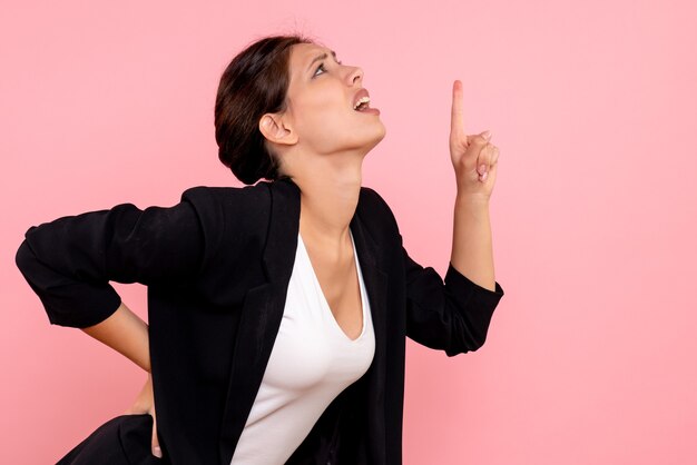 Front view young female in dark jacket having back ache on pink background