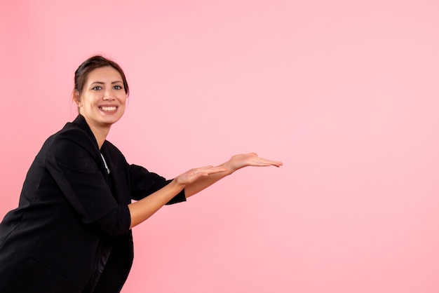 ピンクの背景に暗いジャケットの正面図若い女性