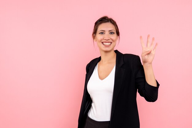 Front view young female in dark jacket smiling on a pink background