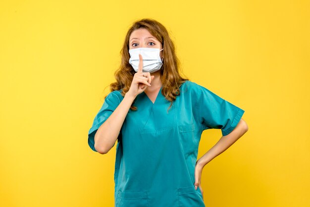 Front view young female doctor asking to be quiet on yellow space