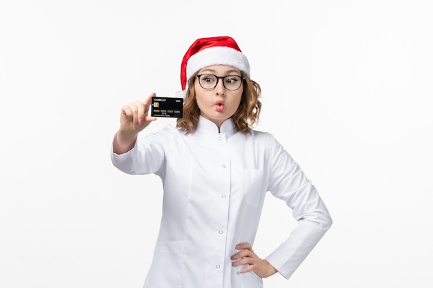 Front view young female doctor holding bank card on a white wall holiday nurse new year