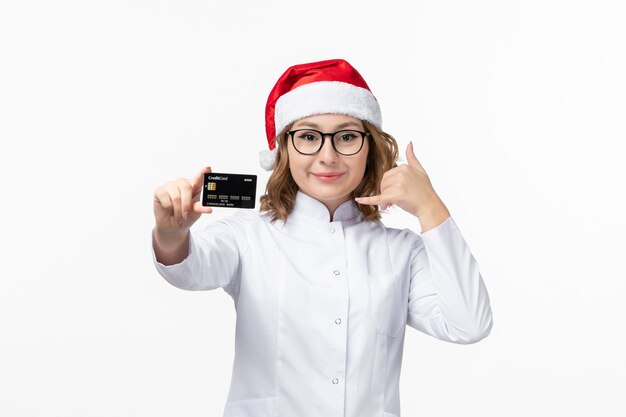 Front view young female doctor holding bank card on a white wall money nurse new year