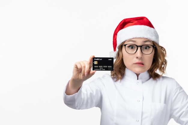 Front view young female doctor holding bank card on white wall money nurse new year