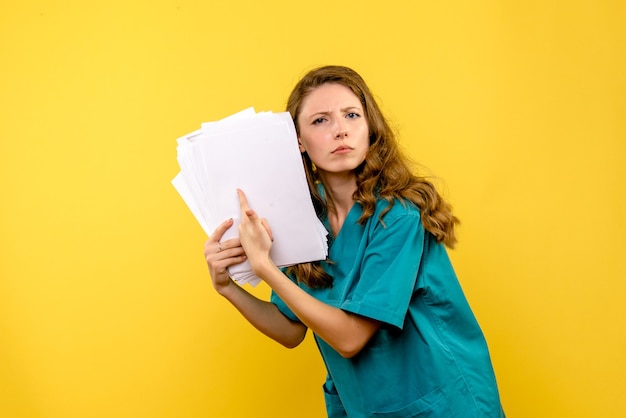 Front view young female doctor holding files on a yellow space