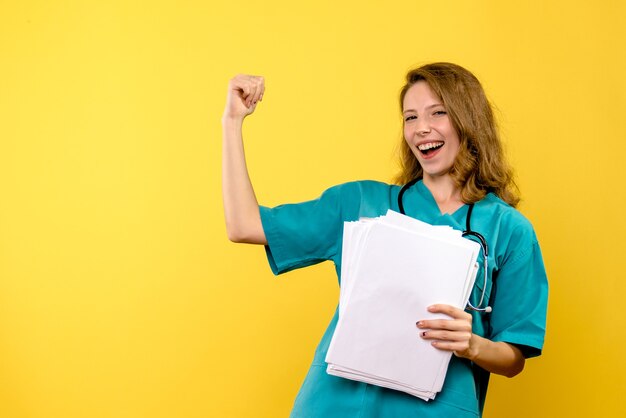 Front view young female doctor holding files on yellow space