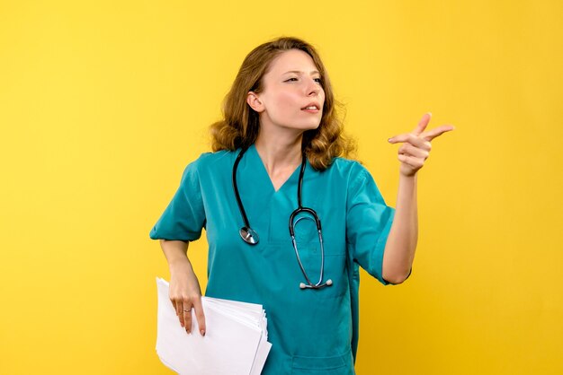 Front view young female doctor holding files on yellow space