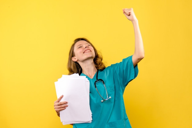 Front view young female doctor holding files on yellow space