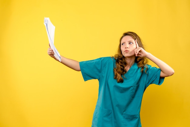 Front view young female doctor holding files on yellow space