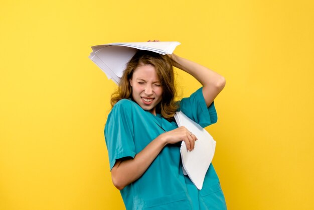 Front view young female doctor holding files on yellow space