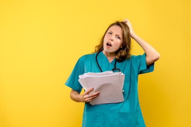 Front view young female doctor holding files on yellow space