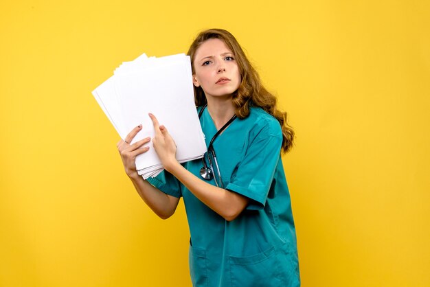 노란색 공간에 파일을 들고 전면보기 젊은 여성 의사