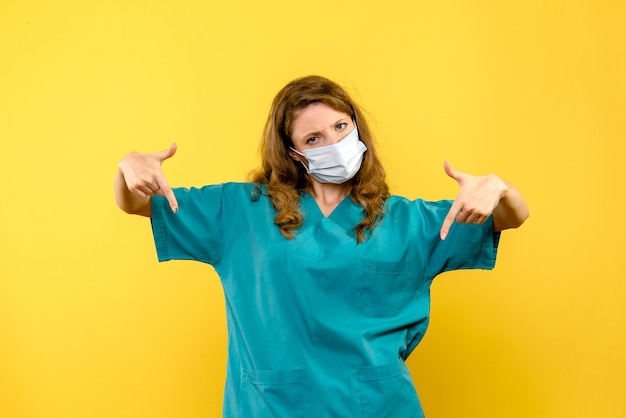 Front view young female doctor in mask on yellow space