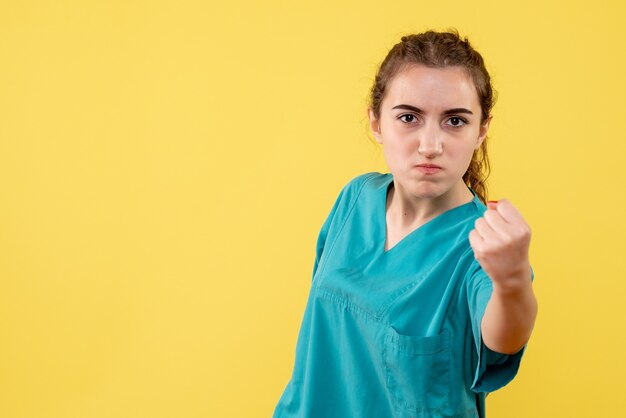 Front view of young female doctor in medical shirt angry on yellow wall