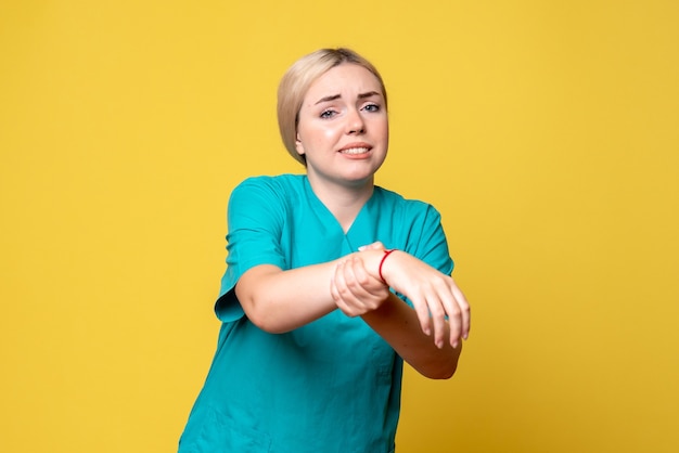 노란색 벽에 상처 손으로 의료 셔츠에 젊은 여성 의사의 전면보기