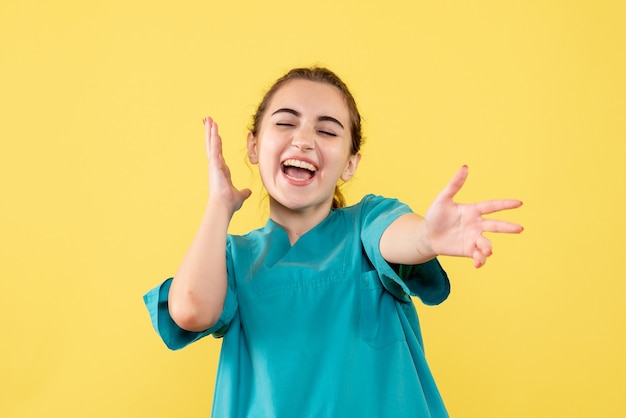 Front view of young female doctor in medical shirt on the yellow wall