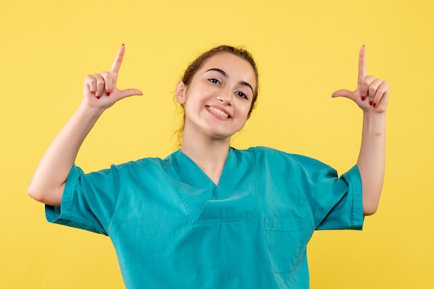 Free photo front view of young female doctor in medical shirt on yellow wall