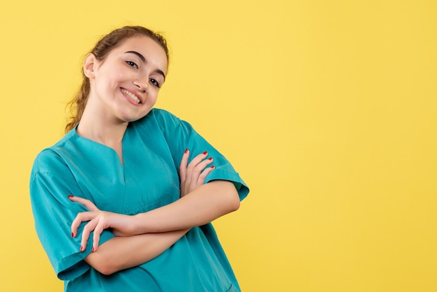 Foto gratuita vista frontale del giovane medico femminile in camicia medica sulla parete gialla