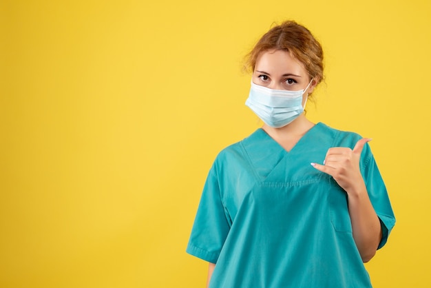 Free photo front view of young female doctor in medical suit and mask on a yellow wall