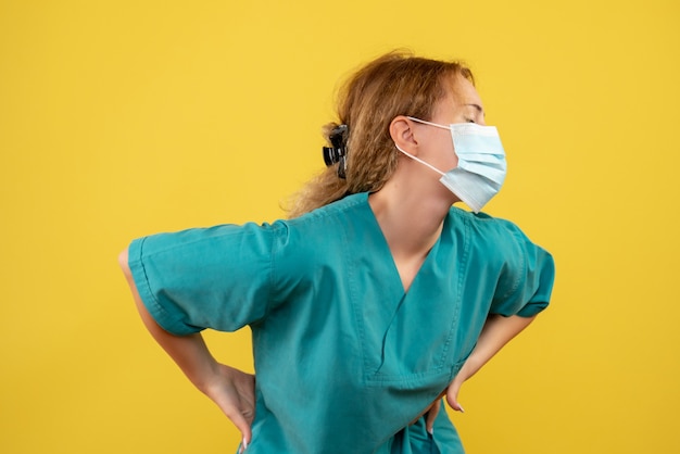 Free photo front view of young female doctor in medical suit and mask on yellow wall