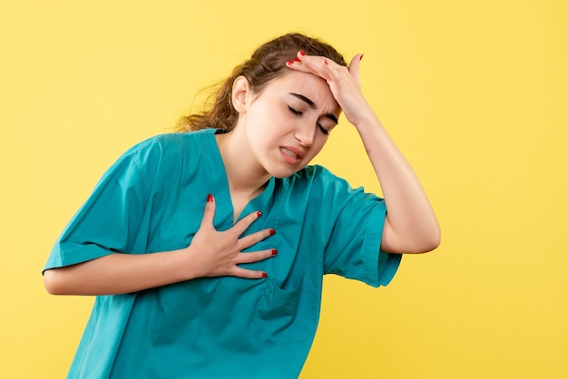 Foto gratuita vista frontale giovane dottoressa in tuta medica con mal di testa su sfondo giallo