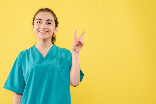 Front view young female doctor in medical suit on yellow background