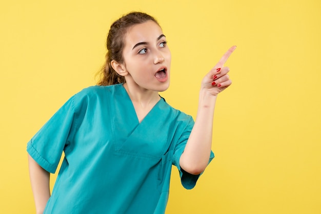 Front view young female doctor in medical suit on yellow background