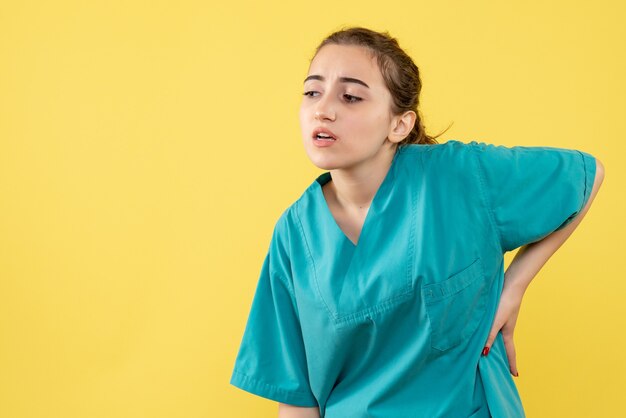 黄色の背景に医療スーツを着た若い女性医師の正面図