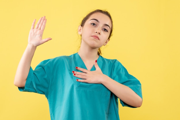 Foto gratuita giovane medico femminile di vista frontale in vestito medico su priorità bassa gialla