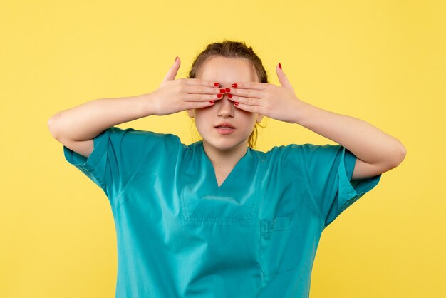 Front view young female doctor in medical suit on yellow background