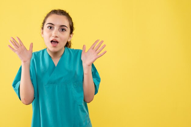 Front view of young female doctor in medical suit on yellow wall