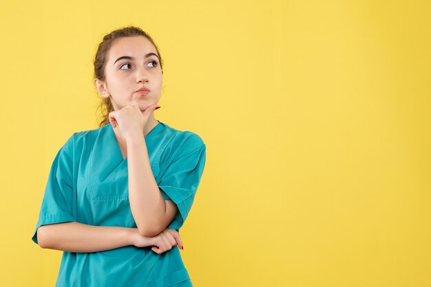 Front view of young female doctor in medical suit on yellow wall