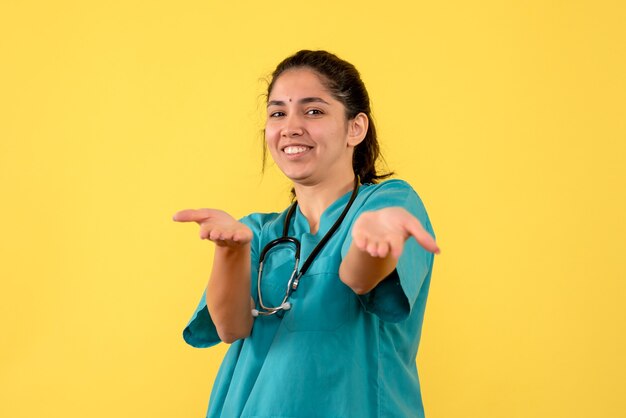 Front view of young female doctor pointing at something on yellow wall