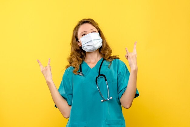 Front view young female doctor posing in mask on yellow space