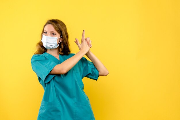 Front view young female doctor posing in mask on yellow space