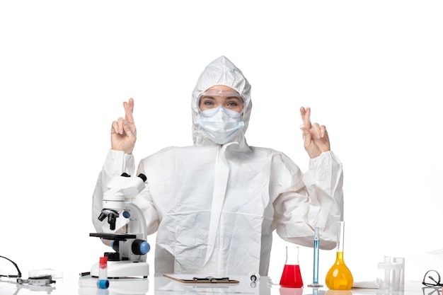 Free photo front view young female doctor in protective suit with mask due to covid crossing her fingers on white background virus pandemic splash covid-