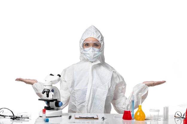 Front view young female doctor in protective suit with mask due to covid on white desk disease health pandemic covid virus