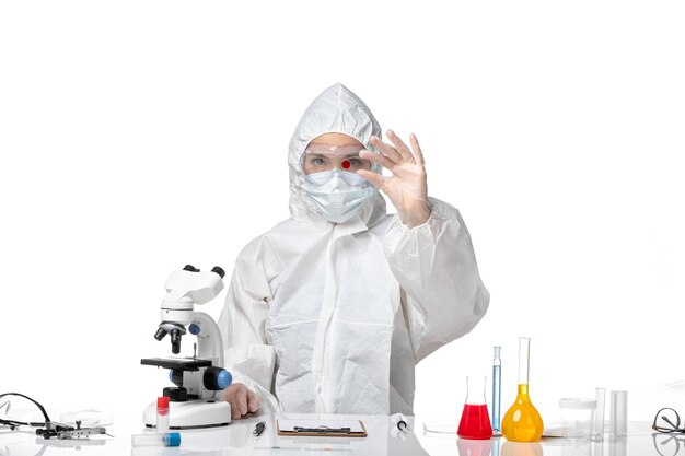 Вид спереди молодая женщина-врач в защитном костюме с маской из-за covid, работающего на белом фоне, здоровье пандемического вируса covid